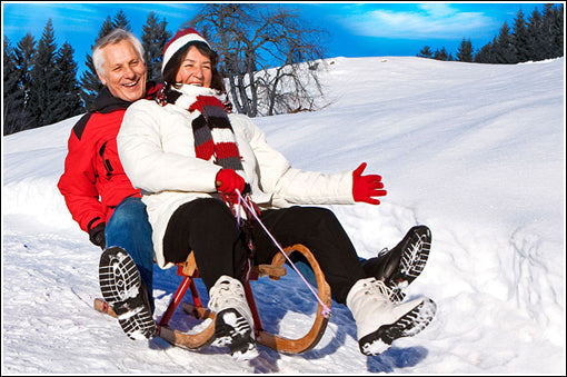 older couple riding a snow sled