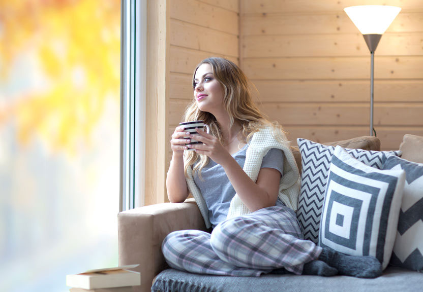 young woman drinking a hot drink looking out the window