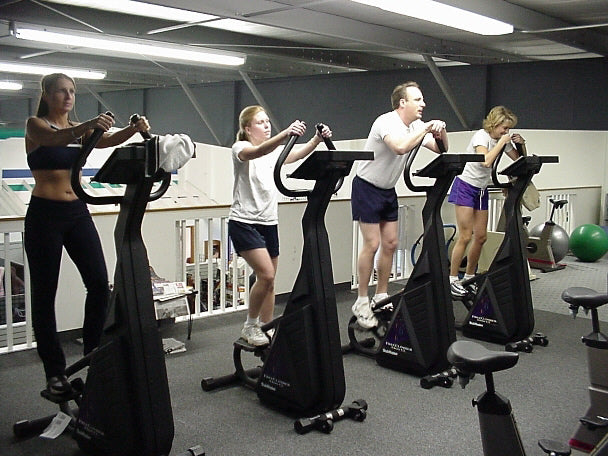 people working out on stairmasters at the gym