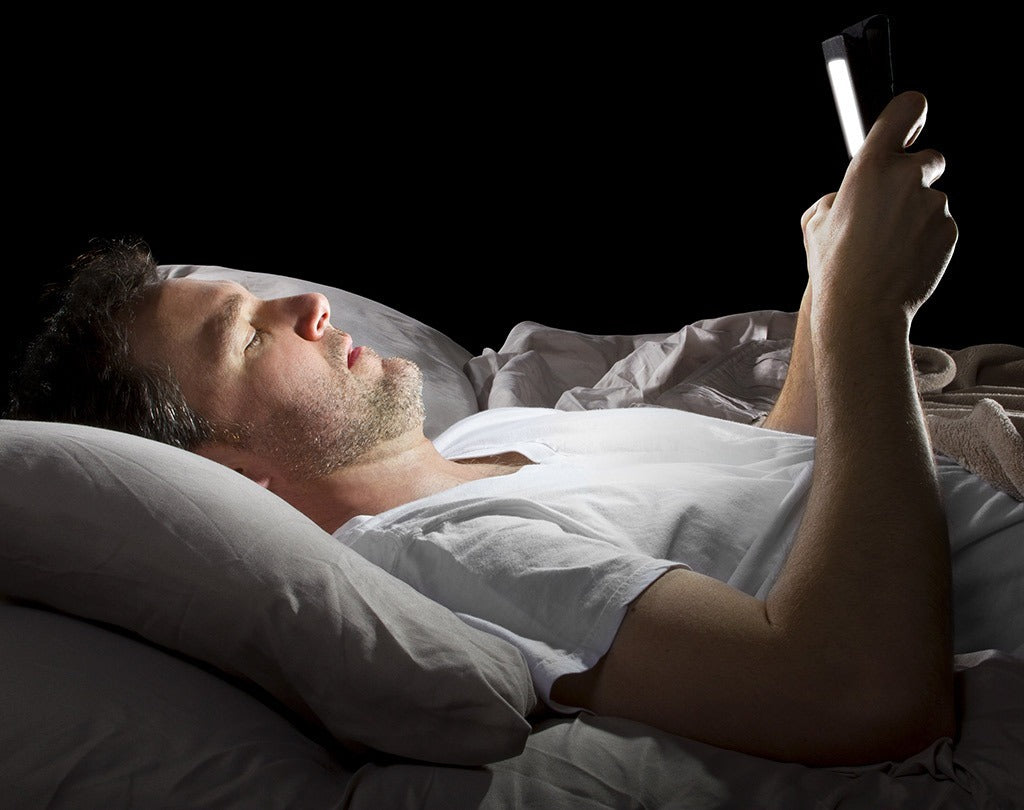 man in bed at night reading his cell phone