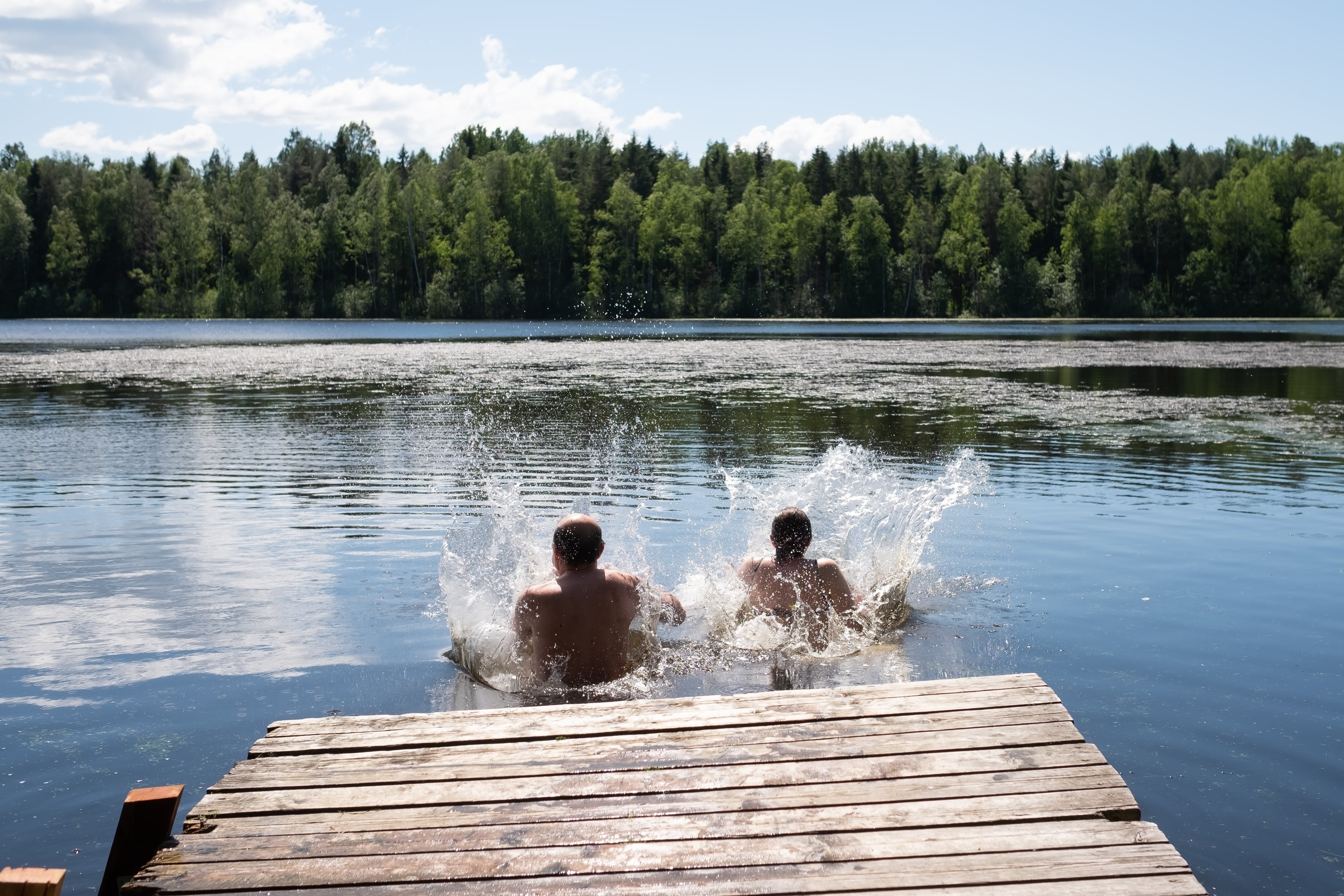 people jumping into a lake