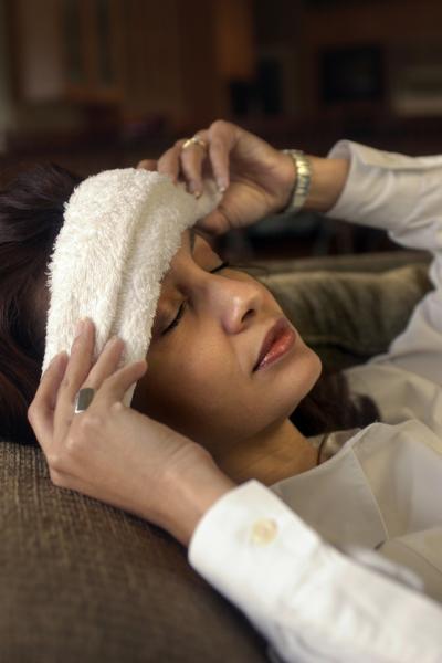 woman laying down with cold wash cloth on head