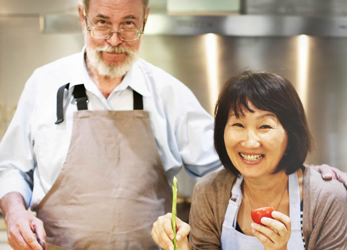 middle aged couple cooking with vegetables