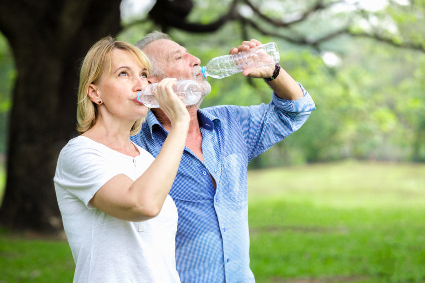 middle-aged couple drinking bottled water outdoors