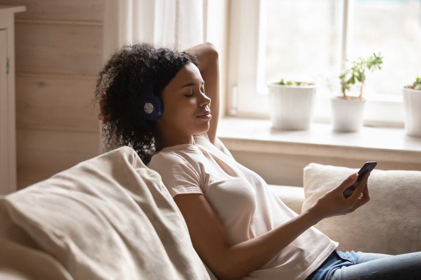 young woman with headphones and cell phone relaxing on sofa