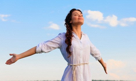 young woman outside with arms outstretched and breathing the outdoor air