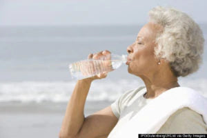 senior woman drinking bottled water at the beach